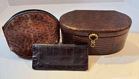 Three items: fur pouch left, leather clutch box right, checkbook cover front