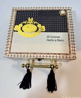 Closed purse front view showing lid graphic, faux pearl, and handle with tassels