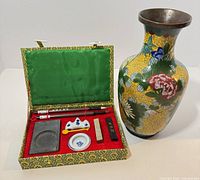 Open calligraphy set with contents beside cloisonné vase