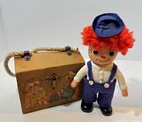 Wooden purse and Raggedy Andy coin bank side by side
