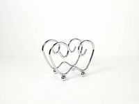 Front view of chrome wire napkin holder showing interlocking heart design and ball feet
