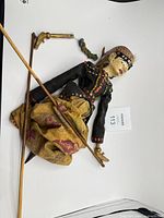 Marionette laid flat with fabric skirt and control rods visible