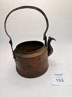 Front view showing bird-form spout, handle upright, missing lid