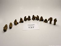 Front view showing all 10 clay figures arranged in arc with lot tag