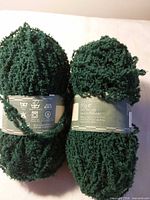 Two dark green yarn balls showing overall appearance with labels