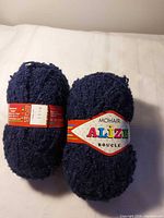 Two navy blue Alize Mohair Boucle yarn balls with labels visible