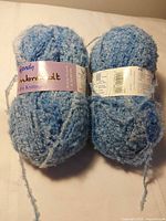 Two blue Wendy yarn balls with labels visible