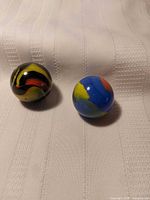 Two marbles on fabric background showing colours and size