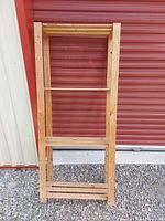 Full view of wooden slatted 4-shelf rack leaning against wall