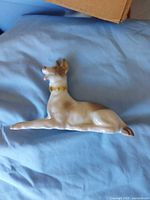 Front angled view of reclining porcelain dog figurine showing coloration and collar