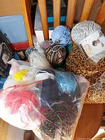 Group of assorted yarn skeins and balls on chair, clear bag with multiple colours