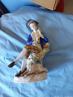 Front view of porcelain figurine showing young man with flute, dog, base details