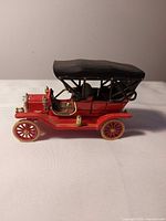 Left front side view of red Ford Model T die-cast car with black roof