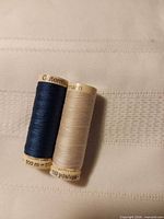 Two Gutermann thread spools side by side showing thread colours and length marking