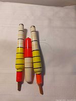 Three long striped fishing bobbers on white cloth