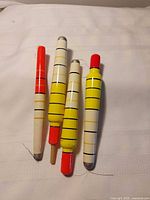 Four long fishing bobbers laid out on surface