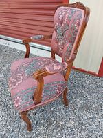 Full side view of carved wood armchair showing arms, legs, and upholstery