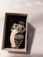 Front view of owl brooch in box showing design, stones, enamel and overall condition