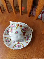 Teacup resting on saucer showing exterior floral and gold design