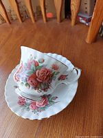 Teacup on saucer showing front rose motif and gold trim