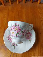 Cup set on saucer showing floral pattern and gold trim
