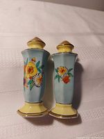 Front view of both ceramic shakers showing floral design, shape and colour