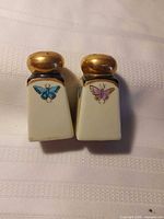 Front view of both shakers showing butterfly decals and gold tops