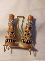 Frontal view of both shakers in metal holder showing decoration