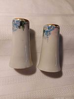 Side view of both porcelain shakers showing floral decoration