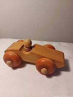 Side view of wooden car showing wheels and driver