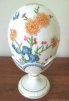 Front view of egg seated on pedestal stand showing primary floral and scroll design
