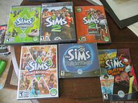 Six The Sims PC game cases laid out on table