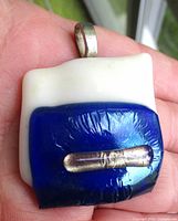 Front view showing white and blue fused glass with purple inset and bail