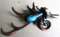 Front view of copper brooch showing turquoise enamel cabochon and curved tendrils