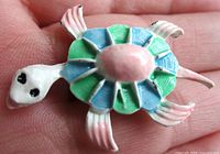 Top view of enamel turtle brooch showing colours and shape