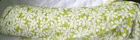 Full roll of green fabric with white daisy pattern