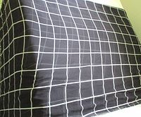 Full view of folded black sheer fabric featuring white grid