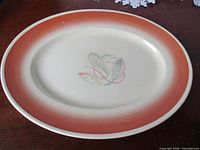 Full view of oval platter showing rim colour and central feather motif