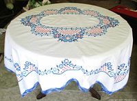 Full view of tablecloth laid on round table showing overall embroidery and crochet trim