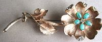 Full view of brooch showing flower, leaves, stem