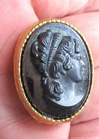 Front view of brooch showing hematite cameo and gold-tone bezel