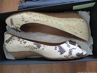 Side view of both shoes in box showing wedge heel and snakeskin print