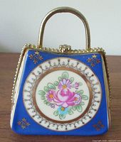 Front view showing purse shape, handle, floral medallion, blue borders, gold trim