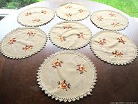 All seven embroidered doilies displayed on table
