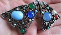 Front view of brooch showing bow shape and array of multicoloured cabochon stones and faux pearls