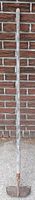 Full view of long scuffle hoe leaning against wall