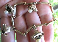 Full view of bracelet on hand showing bell dangles and faux pearls