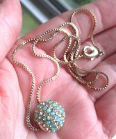 Necklace coiled in hand showing pendant detail and clasp