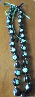 Full view of kukui nut lei necklace laid flat