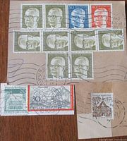 Cluster of ten Heinemann definitive stamps plus two commemorative stamps on envelope pieces